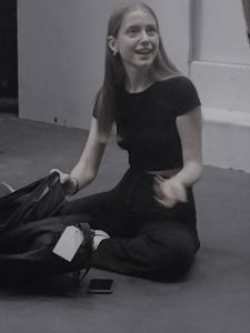 Rehearsal image of actor sitting with a suitcase