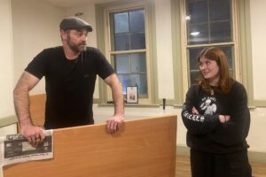 Male and female actor stand talking at an imaginary bar