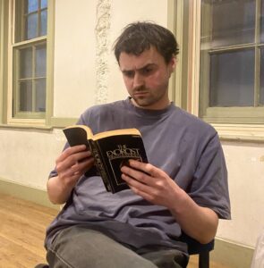 Male actor sits reading a copy of The Exorcist