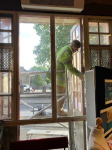 A photograph of a man stripping paint from one of the doors of the SLT Fire Station