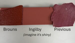 A small piece of wood with two variants of red paint plus a section of the old door paint colour.