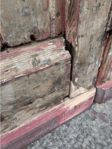 A close up of a bottom of a door, showing more gaps in the joins of the woodwork
