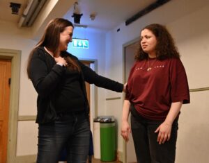 An older woman stands with her hand affectionately on the arm of a younger woman