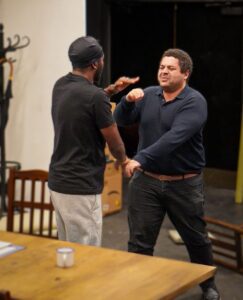 Two men stand facing each other as though fighting