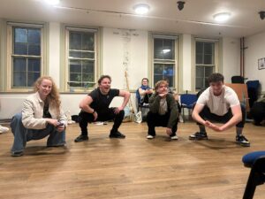 Three male and and a female actor crouch low