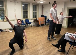 Three male actors singing in various poses