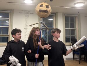 Three young actors standing in rehearsal with puppets in hand