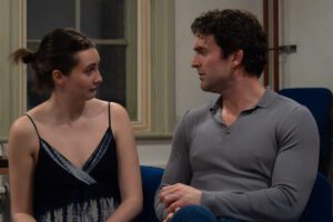 Male and female actor sit talking, facing each other