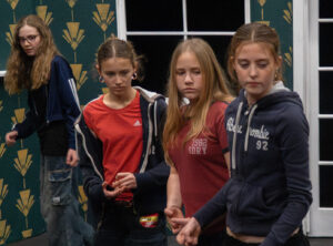 Four young female actors in rehearsal standing and looking in same direction