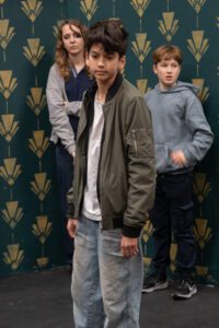 Three young actors standing in rehearsal, looking concerned