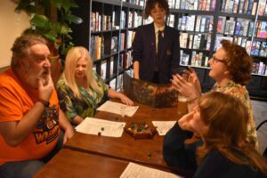 Five people sit around a table, about to play a game