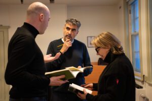 The director stands talking a man and woman mid scene 