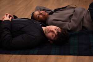 Young man and woman lie head to head o n a picnic blanket