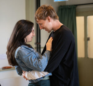 A man holds a woman in his arms in an embrace - both are smiling