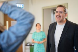 A man remonstrates with a woman standing with her back to the camera, while another looks on