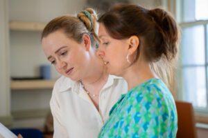 Two women stand close together looking at a text