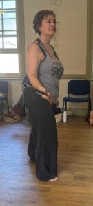 A female actor holding a pistol stands in an assertive pose