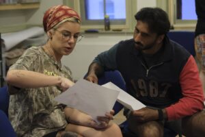 A male and a female actor sit discussion a script