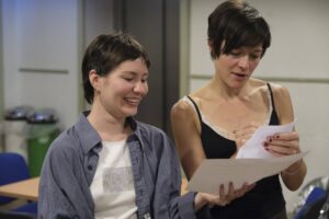 Two female actors stand discussion a script