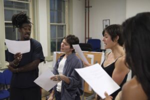 Four actors stand discussing the script