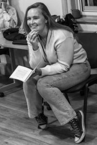 Director Indie sits forward smiling, script in hand.