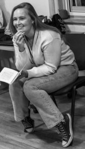 Director Indie sits forward smiling, script in hand.