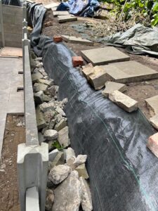 A picture showing the creation of a new yard wall with a draining runaway next to the wall.