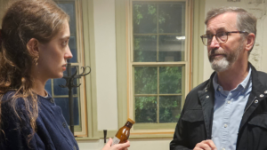 A woman holding a medicine bottle in conversation with an older man